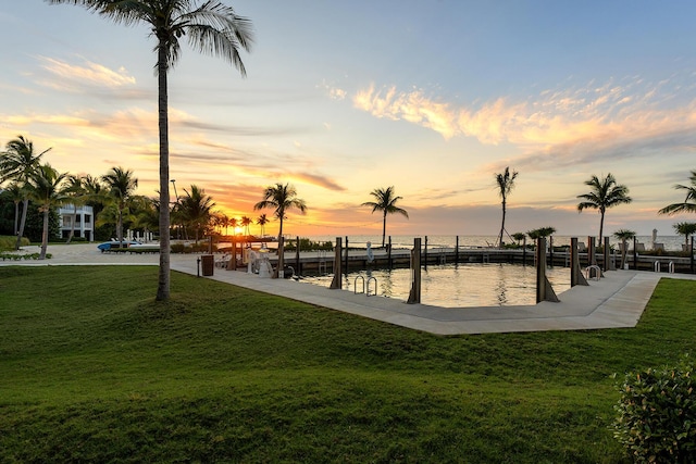 view of community with a dock, a lawn, and a water view