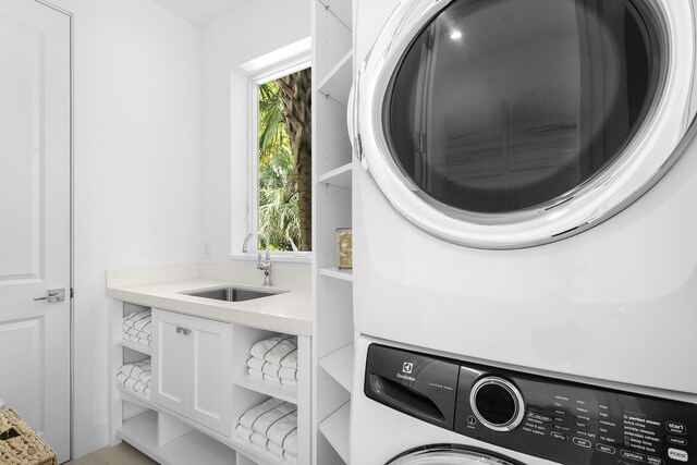 laundry room with stacked washer and dryer, sink, and a healthy amount of sunlight