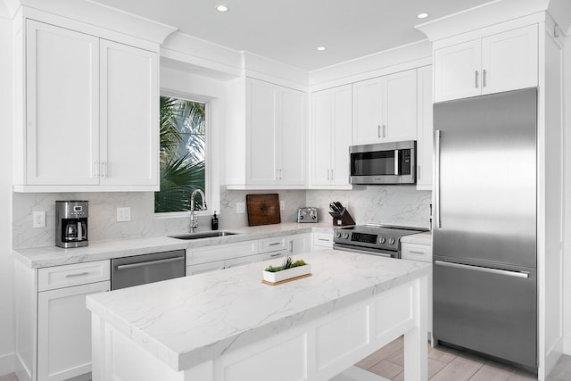 kitchen featuring sink, appliances with stainless steel finishes, light stone countertops, white cabinets, and a kitchen island