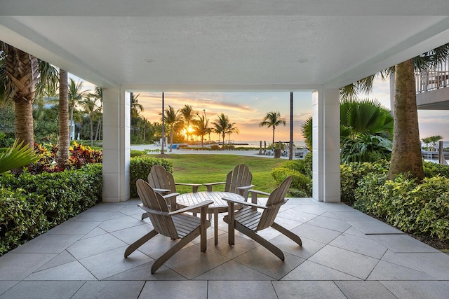 patio terrace at dusk featuring a lawn