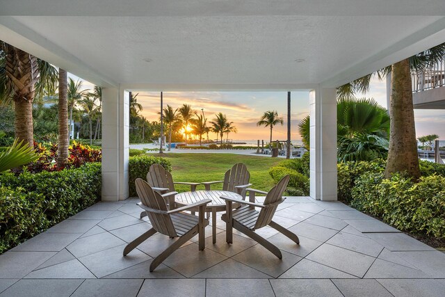 patio terrace at dusk featuring a lawn