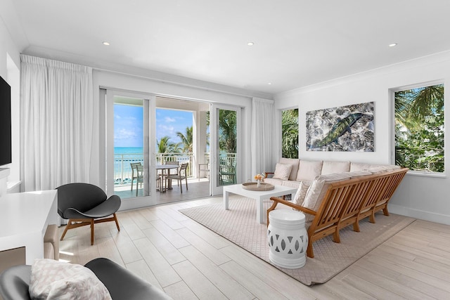 living room featuring a water view, crown molding, and light wood-type flooring