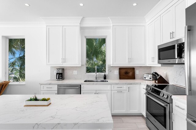 kitchen with stainless steel appliances, a healthy amount of sunlight, white cabinets, and backsplash