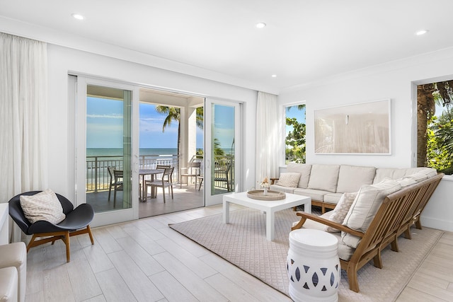 living room with ornamental molding, a water view, and light hardwood / wood-style flooring