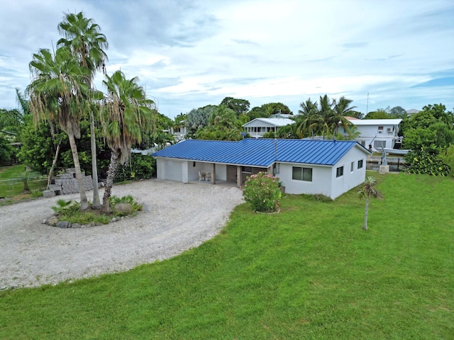 ranch-style home featuring gravel driveway, stucco siding, a standing seam roof, metal roof, and a front lawn