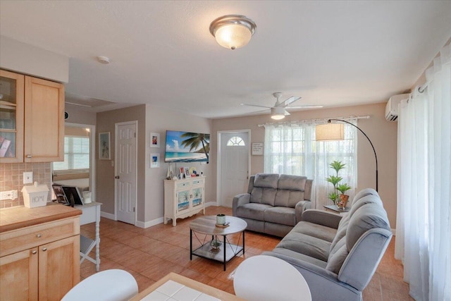 living area with light tile patterned floors, baseboards, plenty of natural light, and an AC wall unit