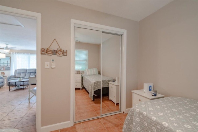 bedroom featuring light tile patterned floors, a closet, and baseboards