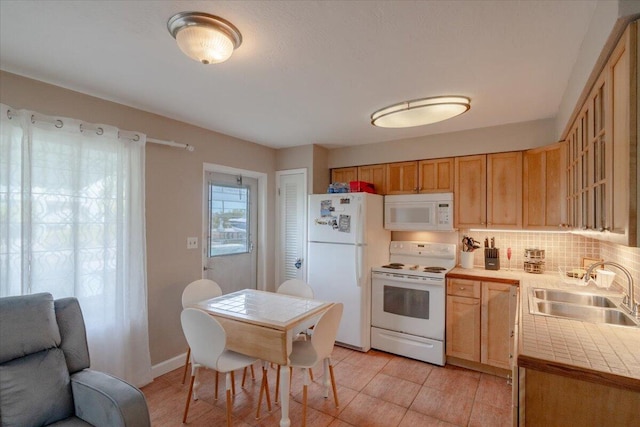 kitchen with glass insert cabinets, tile countertops, decorative backsplash, white appliances, and a sink