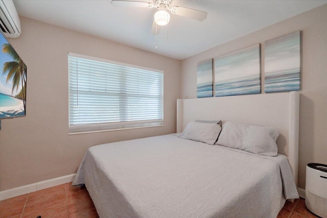 bedroom with an AC wall unit, a ceiling fan, baseboards, and tile patterned floors