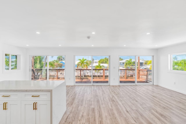 unfurnished living room with recessed lighting, baseboards, and light wood finished floors