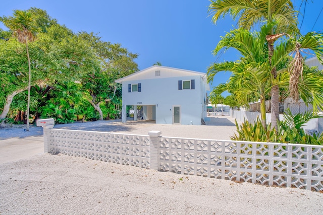 raised beach house featuring a fenced front yard and stucco siding