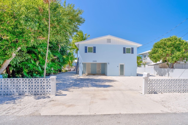 exterior space featuring a fenced front yard, driveway, stairs, and a carport