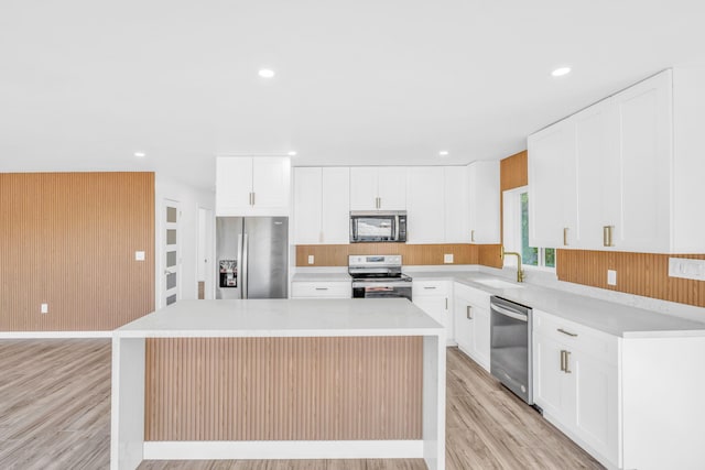 kitchen featuring a sink, a center island, stainless steel appliances, light wood-style floors, and light countertops