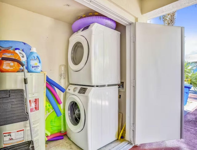 washroom with stacked washer / dryer and water heater