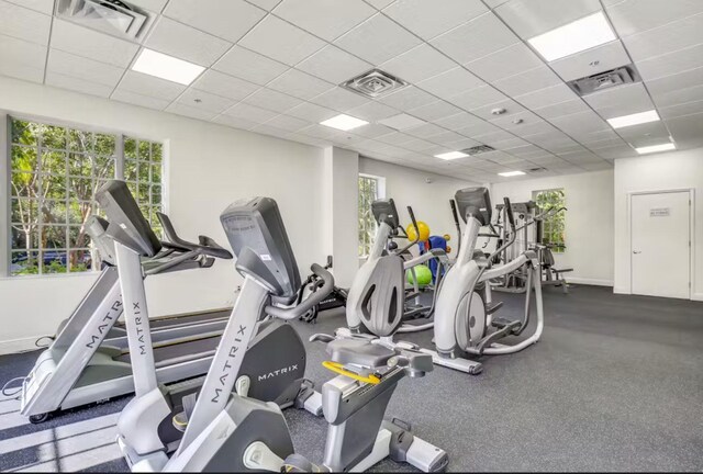 workout area with a paneled ceiling and plenty of natural light