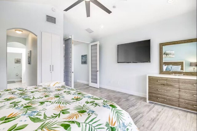 bedroom featuring ceiling fan, ensuite bathroom, high vaulted ceiling, and light wood-type flooring