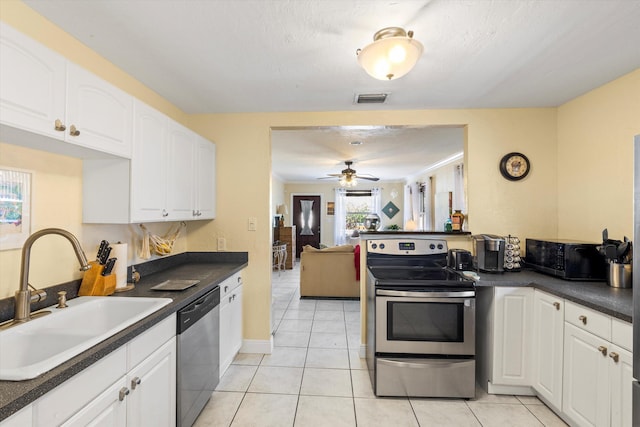 kitchen featuring stainless steel appliances, light tile patterned flooring, sink, and white cabinets