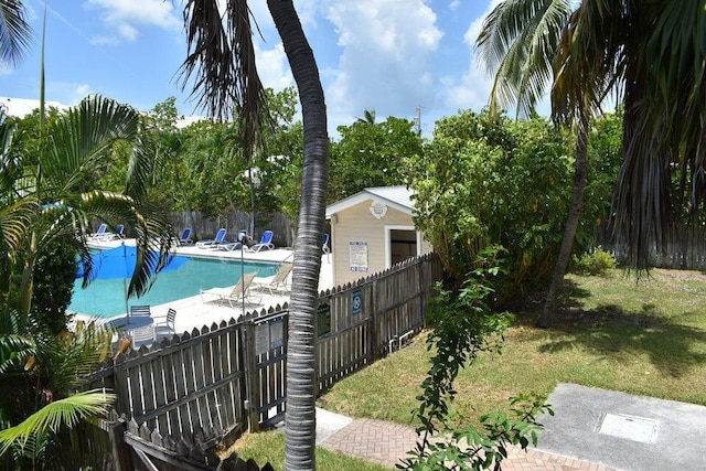 community pool with a fenced backyard and a yard