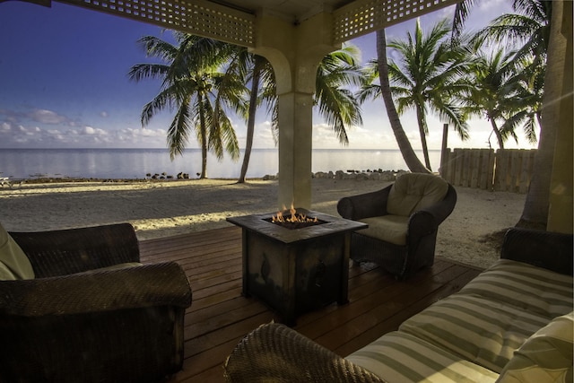 deck at dusk featuring an outdoor fire pit and a water view