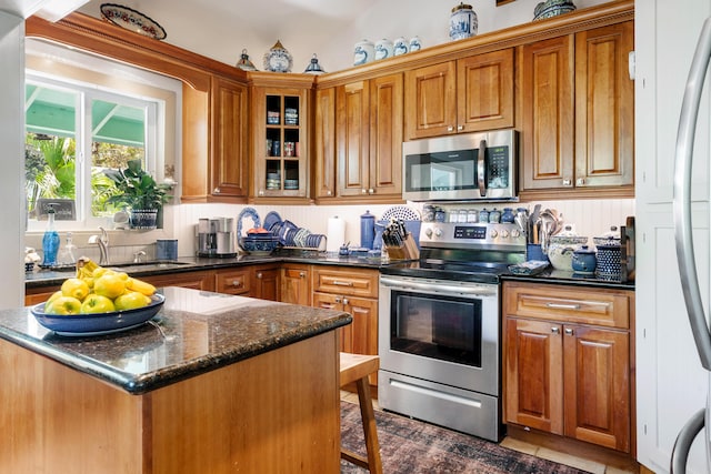 kitchen featuring appliances with stainless steel finishes, sink, and dark stone countertops