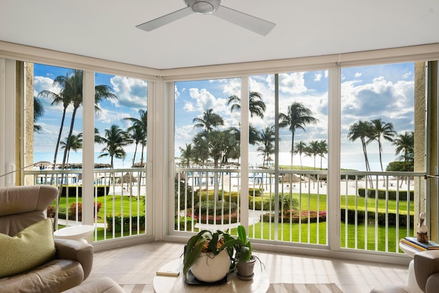 sunroom / solarium featuring a water view and ceiling fan