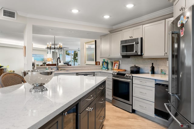 kitchen with light stone counters, stainless steel appliances, hanging light fixtures, and gray cabinetry