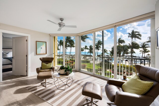 sunroom featuring ceiling fan and a water view