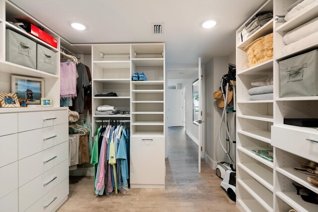 walk in closet with light hardwood / wood-style flooring