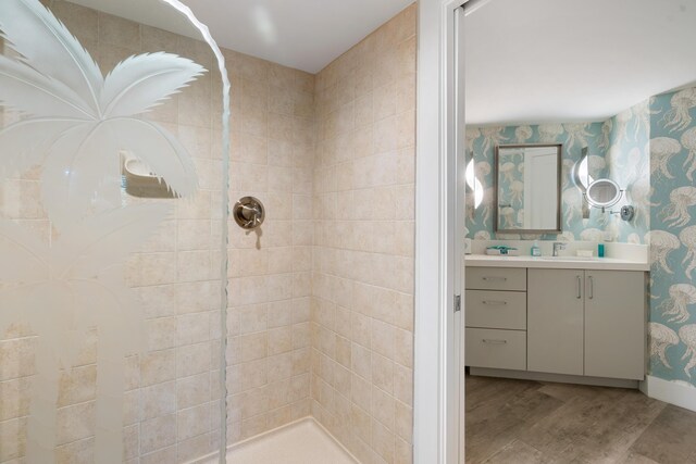 bathroom featuring wood-type flooring, vanity, and a tile shower