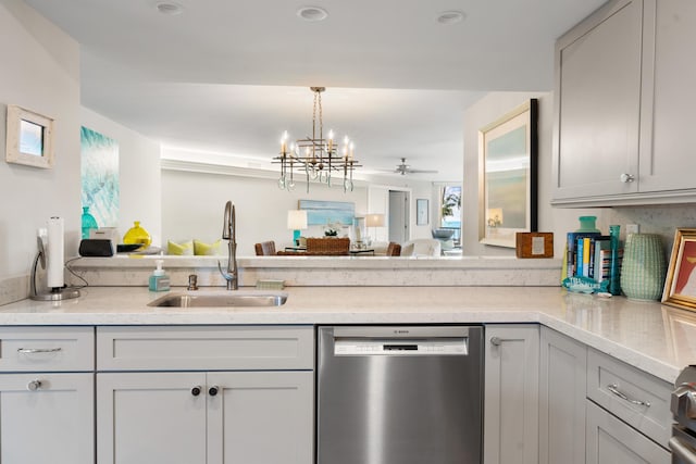 kitchen with sink, light stone counters, stainless steel dishwasher, pendant lighting, and ceiling fan with notable chandelier