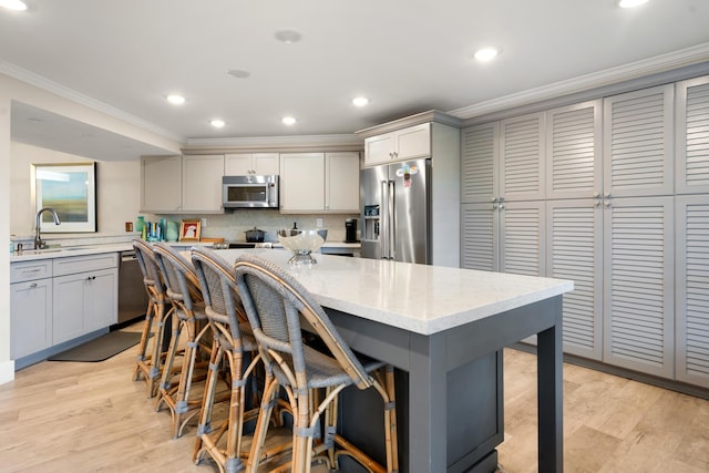 kitchen with sink, gray cabinetry, a kitchen island, stainless steel appliances, and light hardwood / wood-style floors