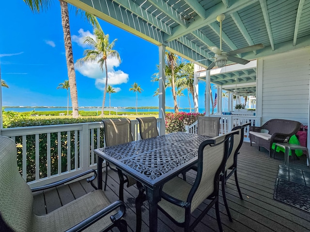 deck featuring a water view, outdoor dining area, and a ceiling fan