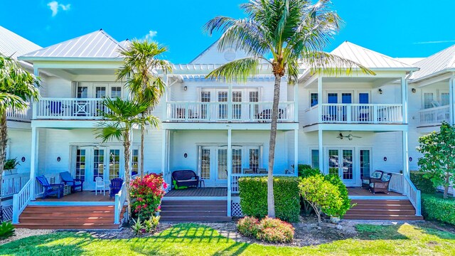back of house with french doors, stucco siding, metal roof, and a balcony
