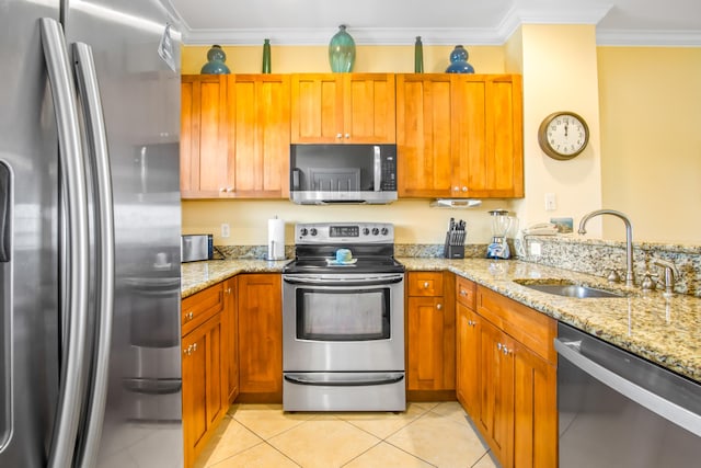 kitchen featuring light tile patterned floors, a sink, ornamental molding, light stone countertops, and stainless steel appliances