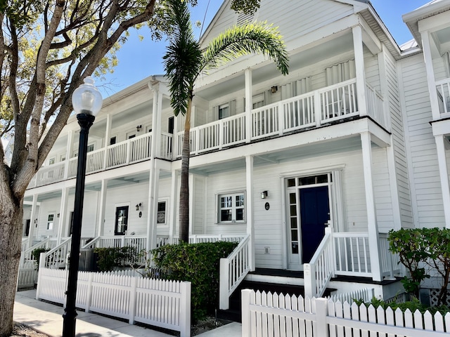 multi unit property featuring a fenced front yard and covered porch