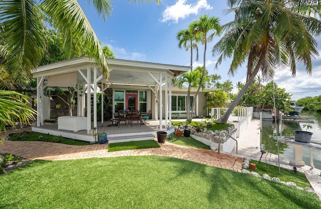 back of property featuring french doors, a water view, and a lawn