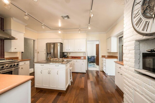 kitchen featuring dark hardwood / wood-style flooring, crown molding, white cabinets, and appliances with stainless steel finishes