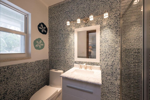 bathroom with vanity, tile walls, and toilet