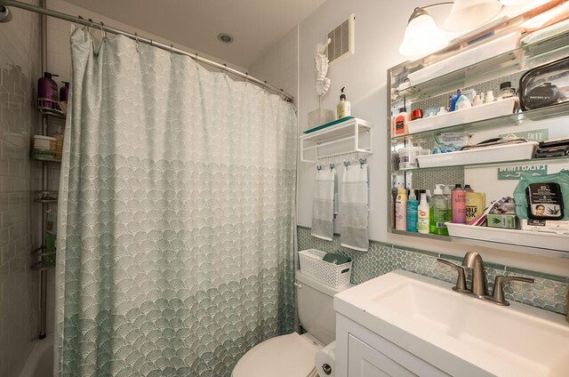 bathroom featuring vanity, toilet, and tile walls