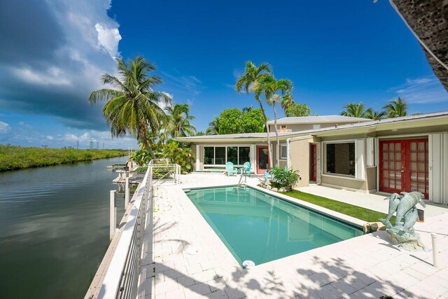 view of swimming pool featuring a patio area, french doors, and a water view