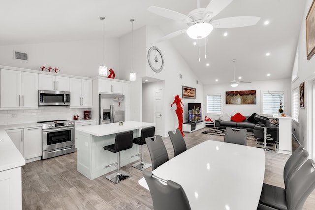 dining area featuring high vaulted ceiling, ceiling fan, and light hardwood / wood-style flooring