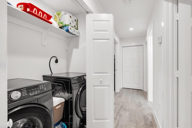 laundry area featuring washer and clothes dryer and light hardwood / wood-style floors