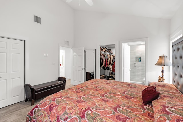 bedroom with ensuite bath, high vaulted ceiling, light wood-type flooring, a closet, and ceiling fan