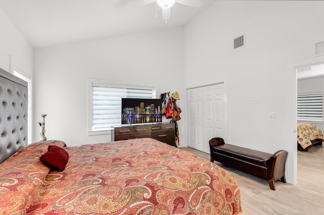 bedroom featuring light hardwood / wood-style flooring, high vaulted ceiling, a closet, and ceiling fan