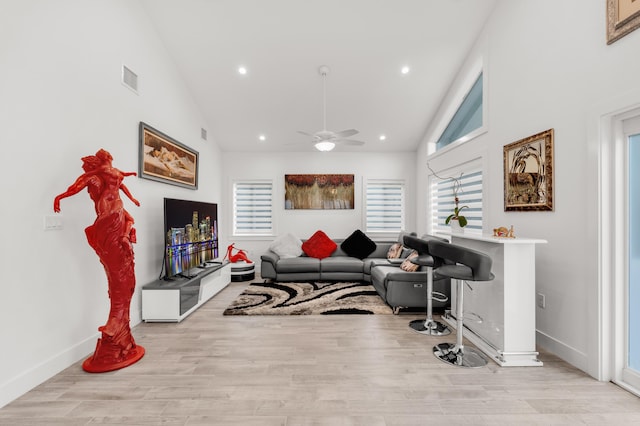 living room featuring ceiling fan, high vaulted ceiling, and light hardwood / wood-style flooring