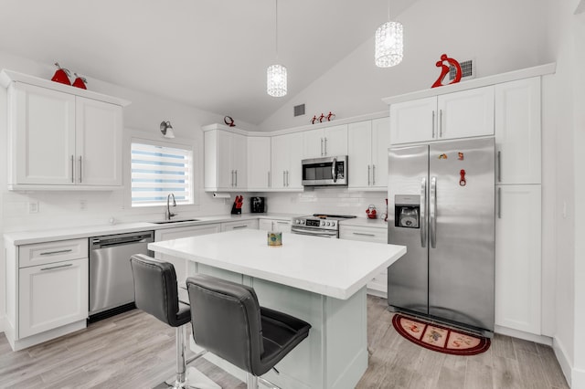 kitchen with a kitchen island, decorative light fixtures, white cabinetry, sink, and stainless steel appliances