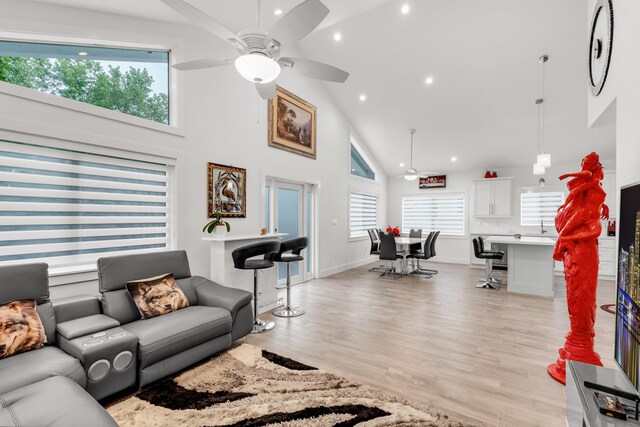 living room with ceiling fan, high vaulted ceiling, and light hardwood / wood-style flooring