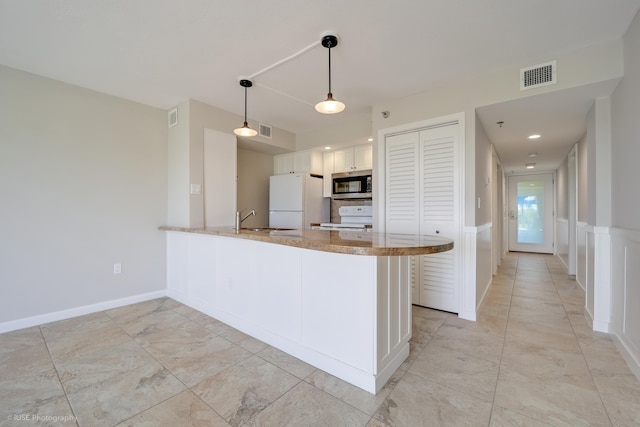 kitchen featuring decorative light fixtures, white cabinetry, sink, kitchen peninsula, and white appliances