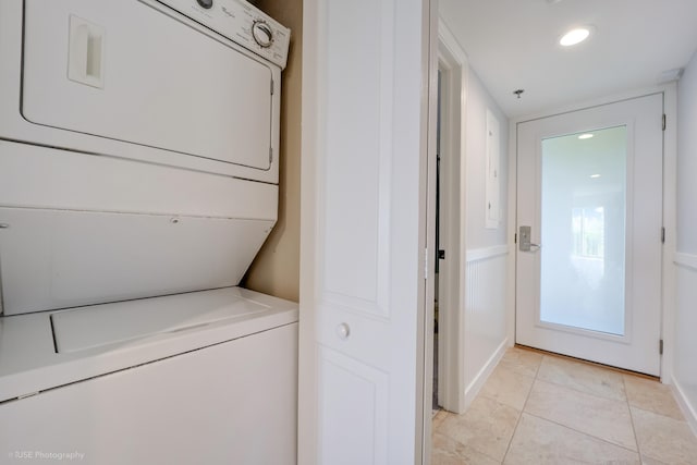 washroom with stacked washer / drying machine and light tile patterned flooring