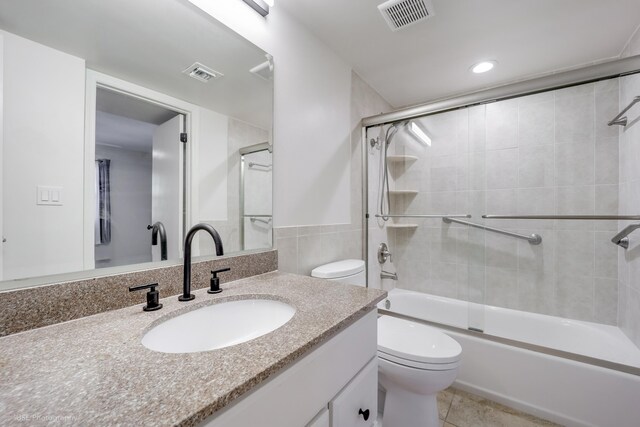 full bathroom with toilet, vanity, bath / shower combo with glass door, and tile patterned flooring